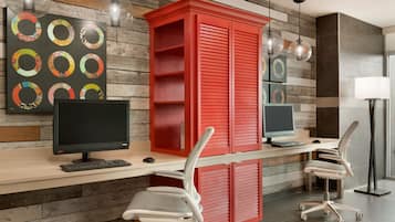 A modern office space with two desks, each with a computer and keyboard, and ergonomic chairs.