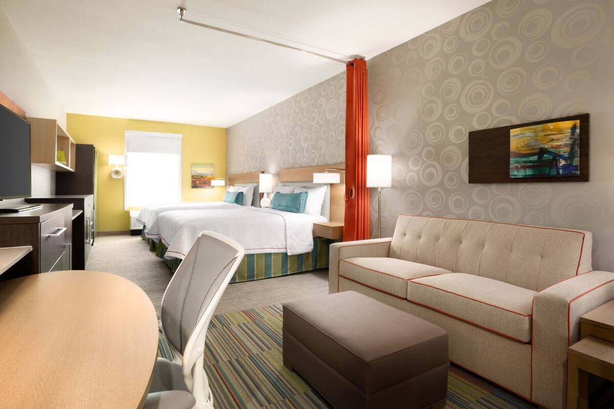 A hotel room with a bed, a sofa, a desk, and a chair.