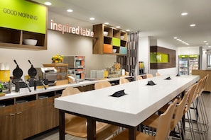 Un moderno comedor con una mesa larga, asientos y diversas opciones para el desayuno.
