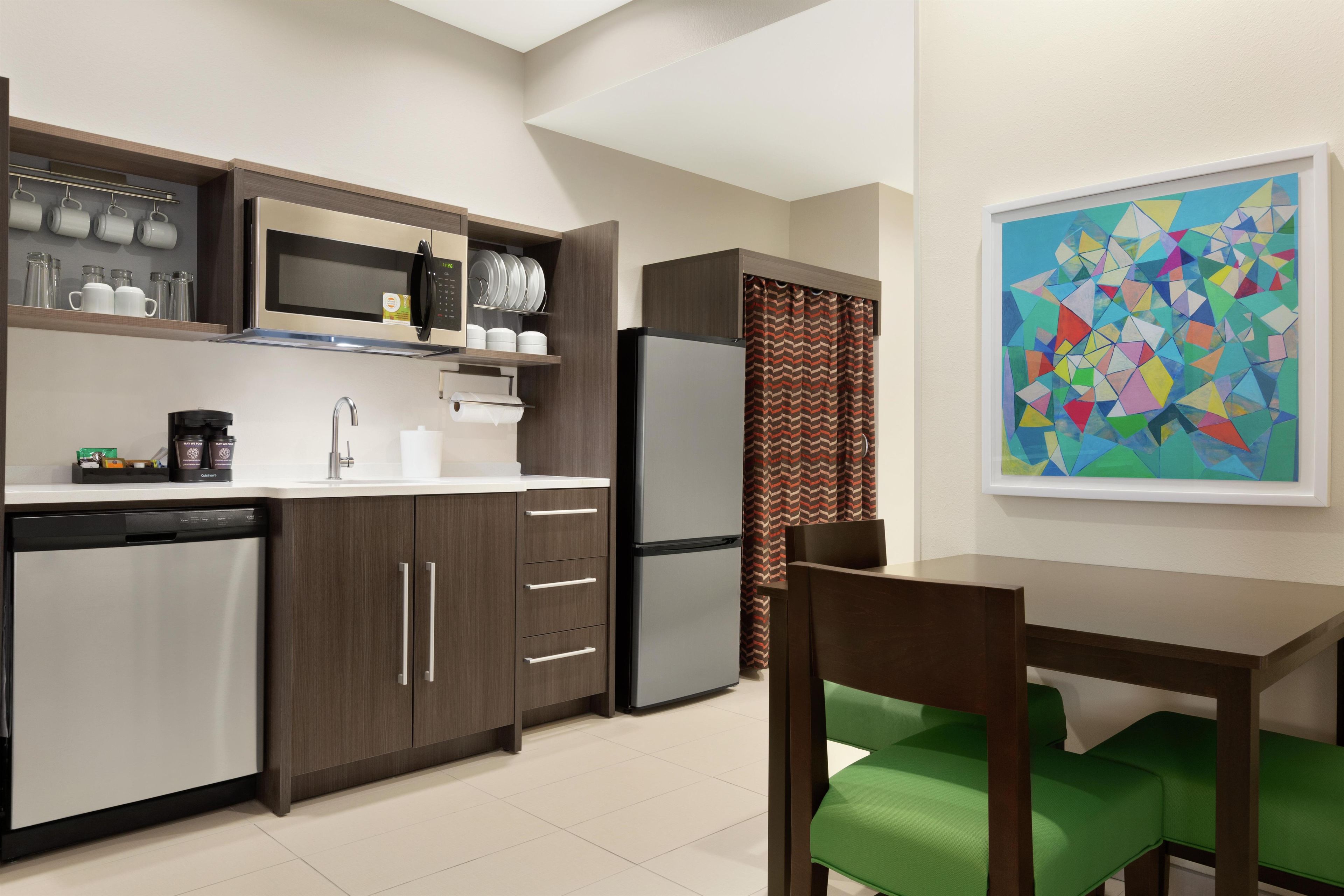 A compact kitchen with a microwave, refrigerator, and a dining area with a chair and table.