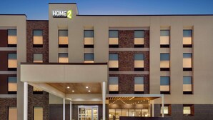 A modern hotel building with multiple floors, a covered entrance area, and a well-lit facade. - Home2 Suites by Hilton Houston-Pearland (Houston)