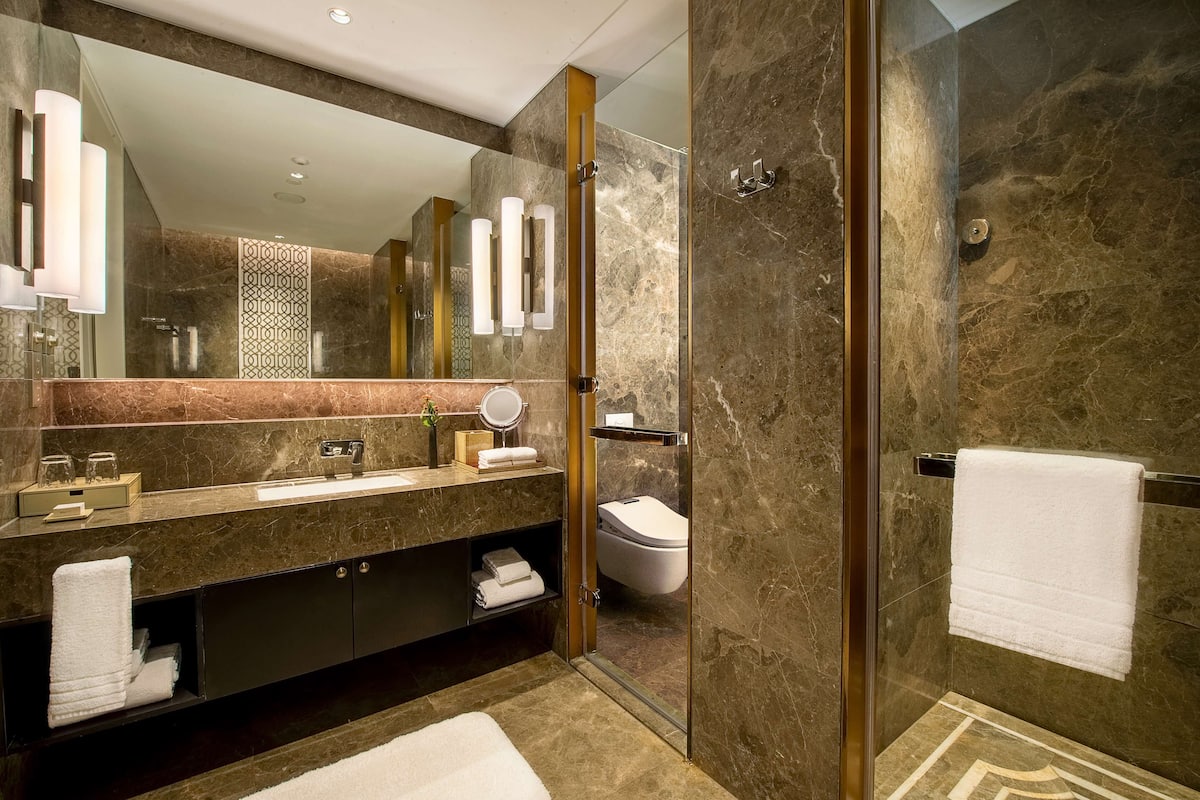 A modern bathroom with a glass-enclosed shower, a marble sink, and a large mirror.
