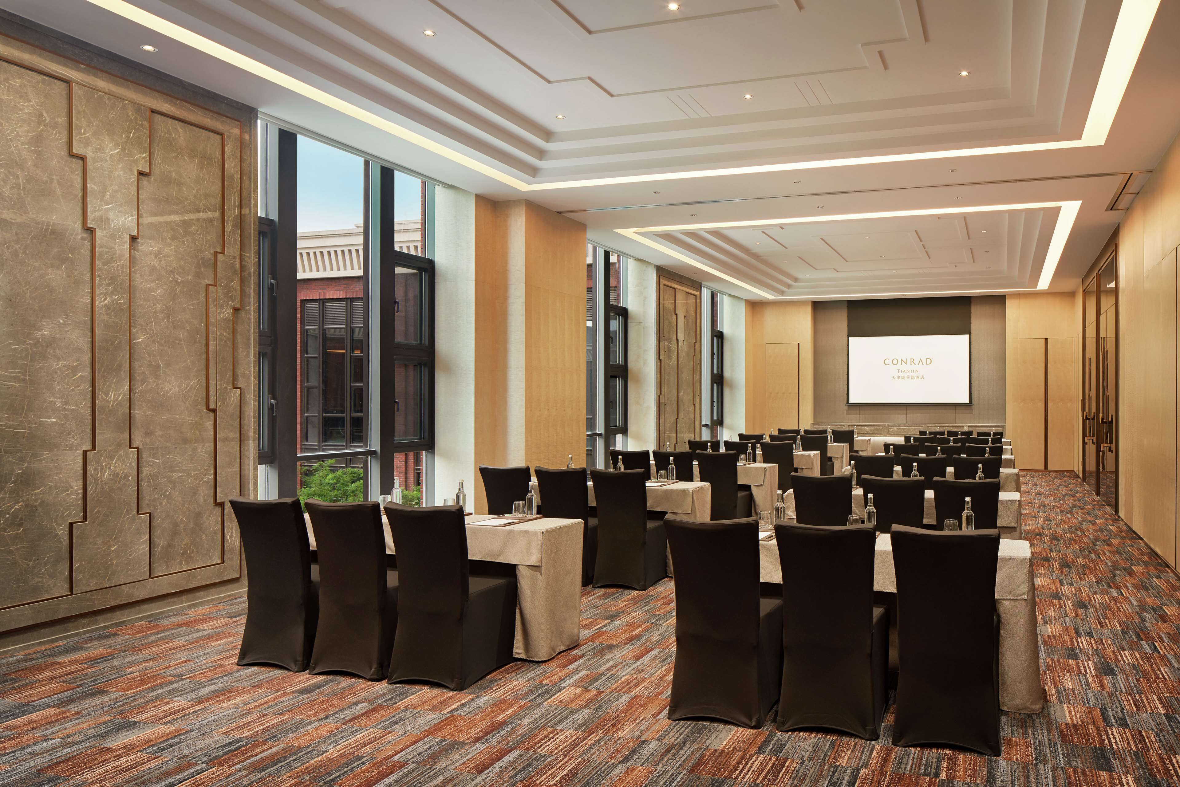 A conference room with tables and chairs, a projector screen, and a large window.