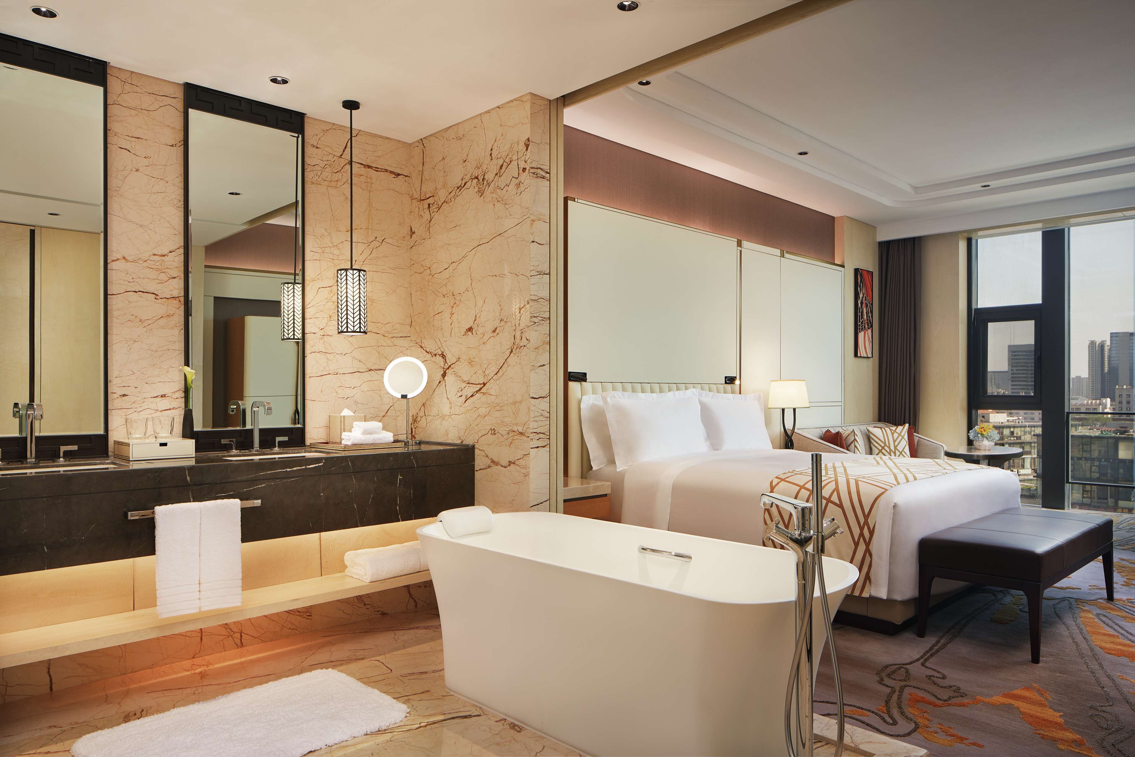 Une chambre d’hôtel moderne dotée d’une grande salle de bain, d’un lit et offrant une vue sur la ville.