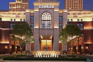 A hotel with a prominent arched entrance, a well-lit facade, and a fountain in the foreground. - Conrad Tianjin (Tianjin)