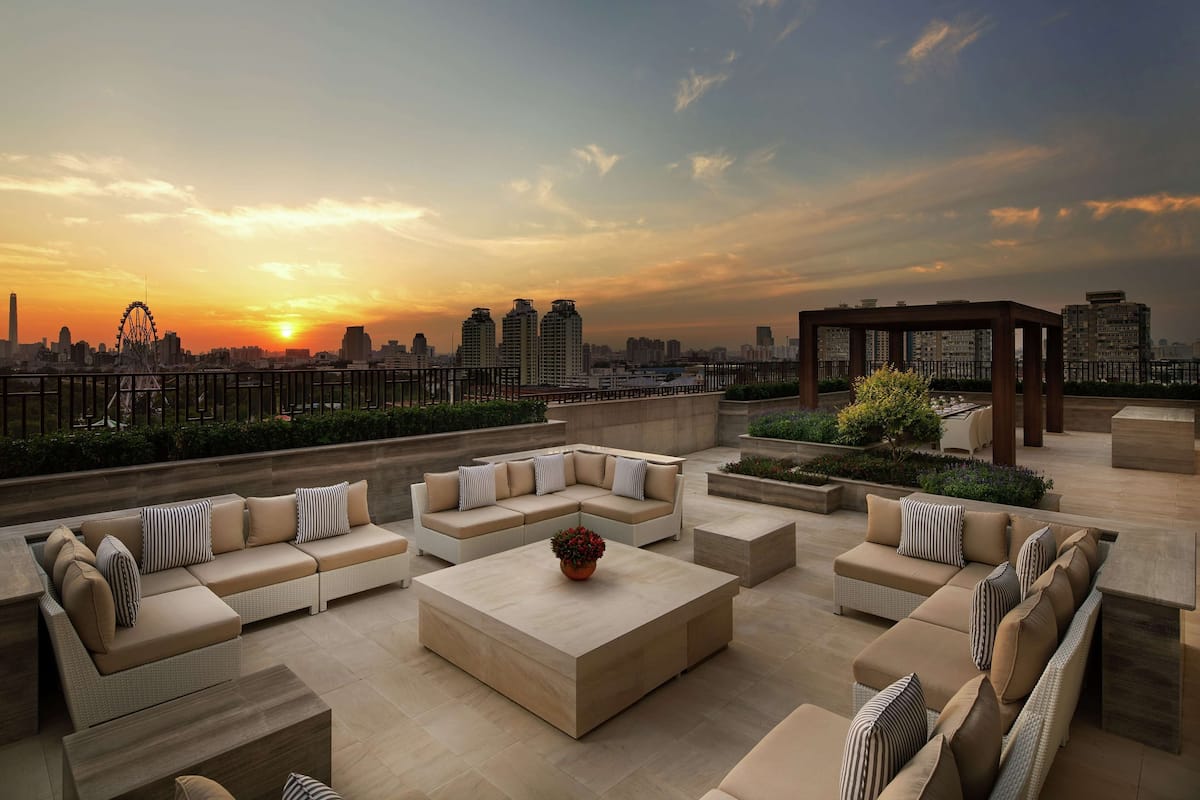 A rooftop terrace with outdoor seating, a view of the city skyline, and a Ferris wheel in the background.