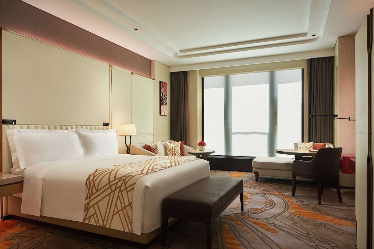 A hotel room with a large bed, a desk, a chair, and a window with a view.