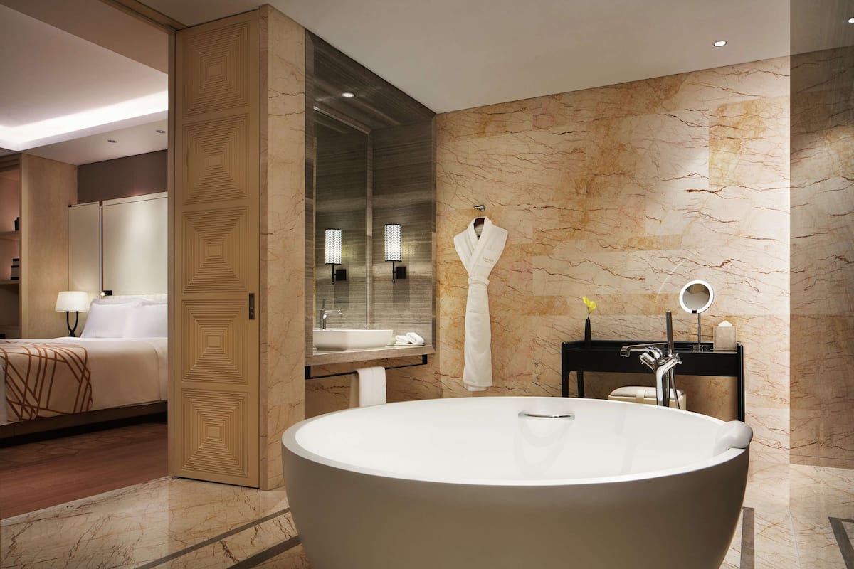A modern bathroom with a freestanding bathtub, a vanity with a mirror, and a robe hanging on the wall.