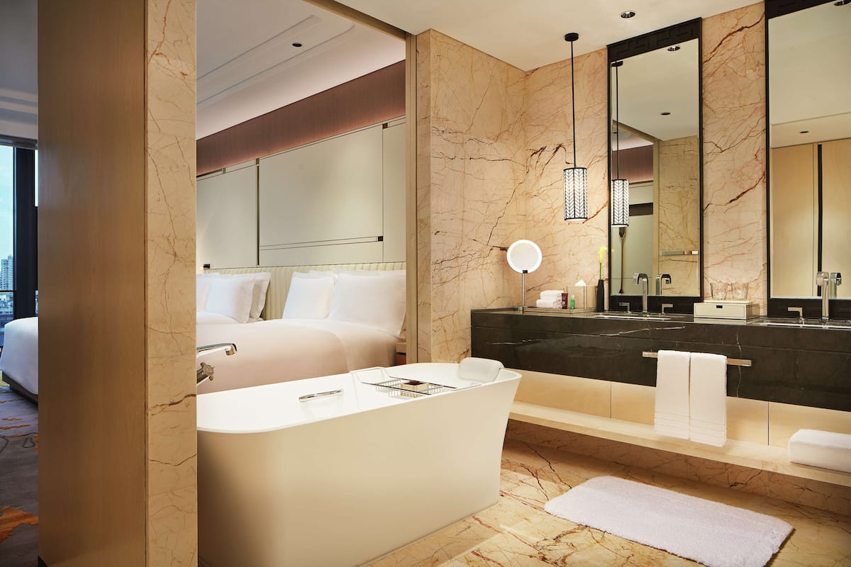 A modern bathroom with a large bathtub, a vanity with a dark countertop, and a large mirror.