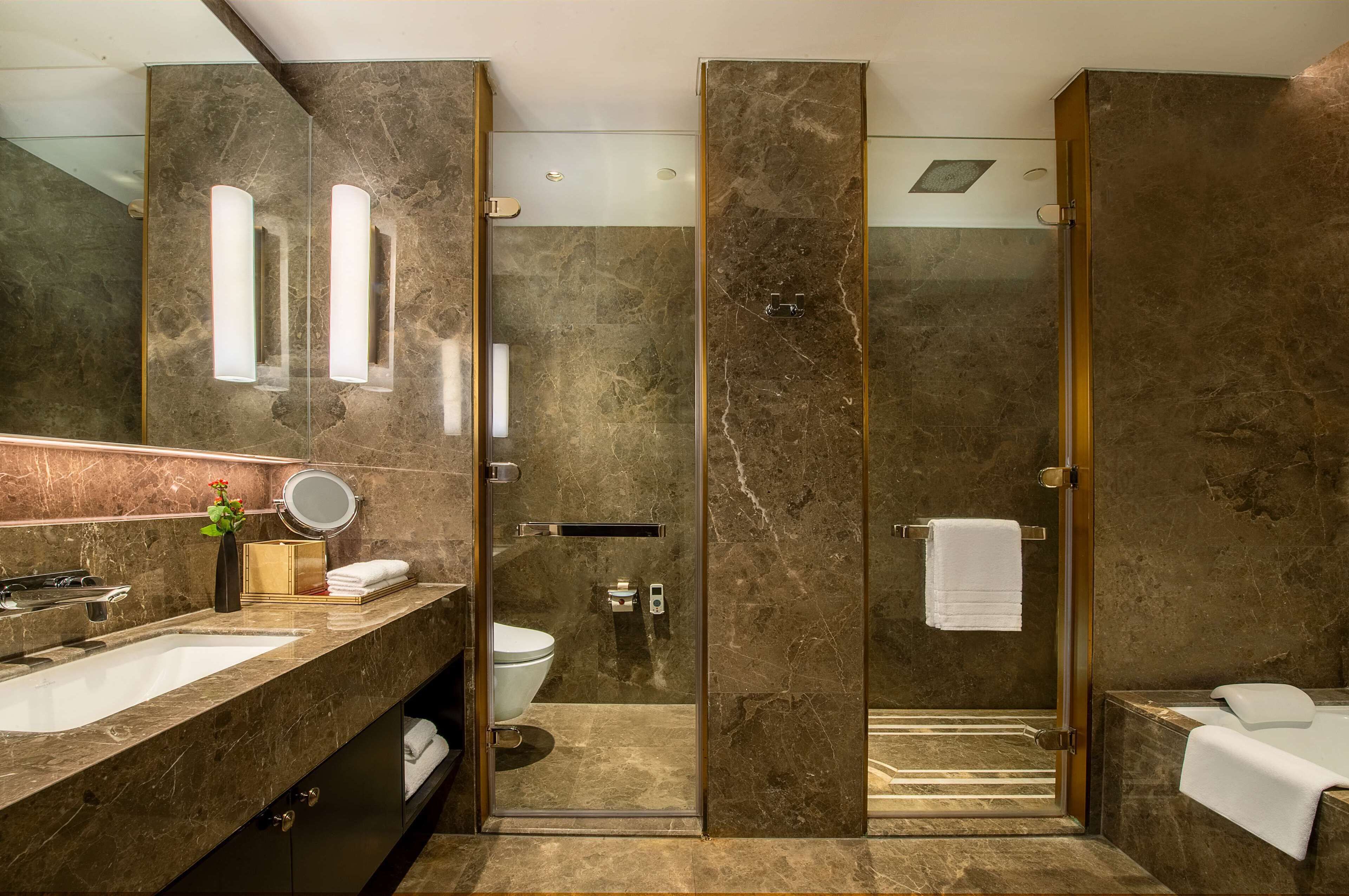 A modern bathroom with a large mirror, a sink, a toilet, a shower, and a bathtub.