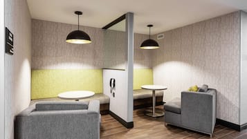 A modern hotel room with a green accent wall, a sofa, a round table, and a mirror.