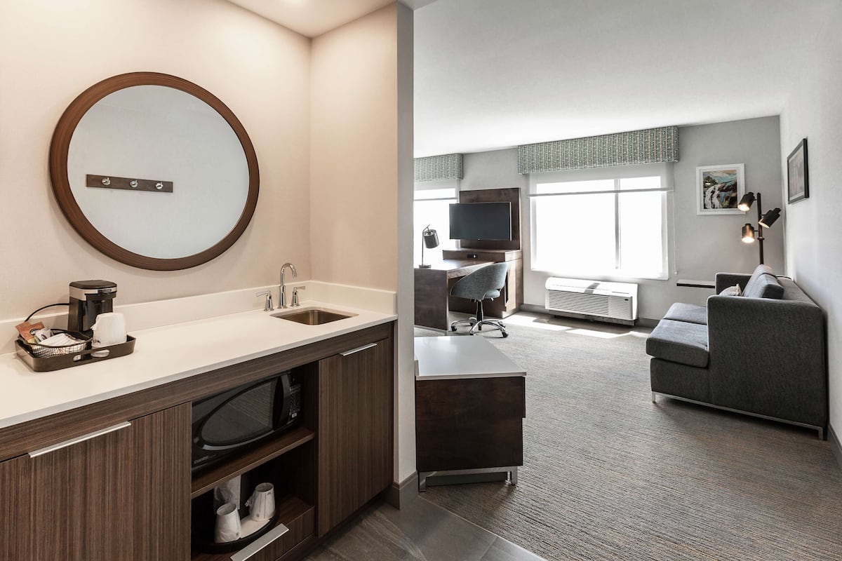 A modern hotel room with a bathroom, a living area, and a seating area.