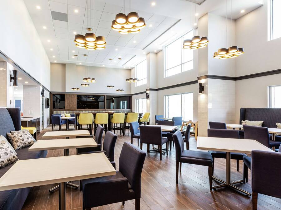 Un restaurante espacioso con varias zonas de comedor, incluyendo cabinas y mesas, y una zona de cocina central.