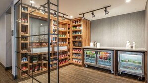 Una despensa bien organizada con estantes llenos de diversos productos alimenticios y dos cámaras frigoríficas.