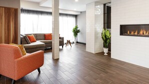 Una sala de estar moderna con chimenea, suelo de madera, un sofá y una planta en maceta.