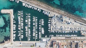 An aerial view of a marina with boats docked in rows, a rocky shoreline, and buildings adjacent to the water. - Llevant - Beautiful villa with pool in Can Picafort (Can Picafort)