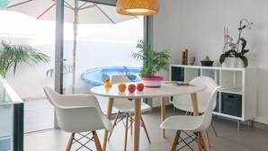 A modern dining area with a round table, white chairs, and a hanging light fixture. - Llevant - Beautiful villa with pool in Can Picafort (Can Picafort)