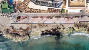 An aerial view of a coastal hotel with a rooftop pool, beachside seating, and a rocky shoreline. - Llevant - Beautiful villa with pool in Can Picafort (Can Picafort)