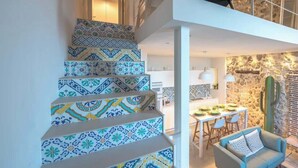 A staircase with patterned tiles, a dining area with a cactus, and a stone wall. - Lio loft, romantic and stunning sea view apt (Syracuse)