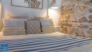 A bedroom with a stone wall, a bed with striped bedding, and a wall-mounted sign. - Lio loft, romantic and stunning sea view apt (Syracuse)
