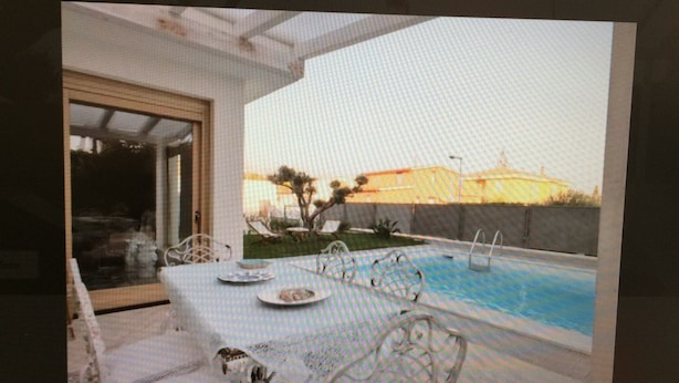 A poolside dining area with a table and chairs, a pool, and a view of the surrounding landscape. - villa in San Leone with swimming pool (san leone agrigento)