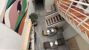Een terras met tafels, stoelen, een trap en een potplant.