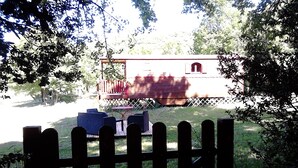Un espace extérieur clos, avec une table et des chaises, un bâtiment en arrière-plan et des arbres.