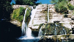 Une cascade à plusieurs niveaux dévalant un terrain rocheux, entourée d’une végétation luxuriante.