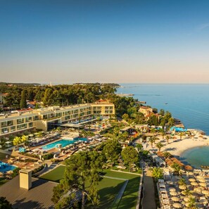 A resort with a swimming pool, beach, and a view of the sea.