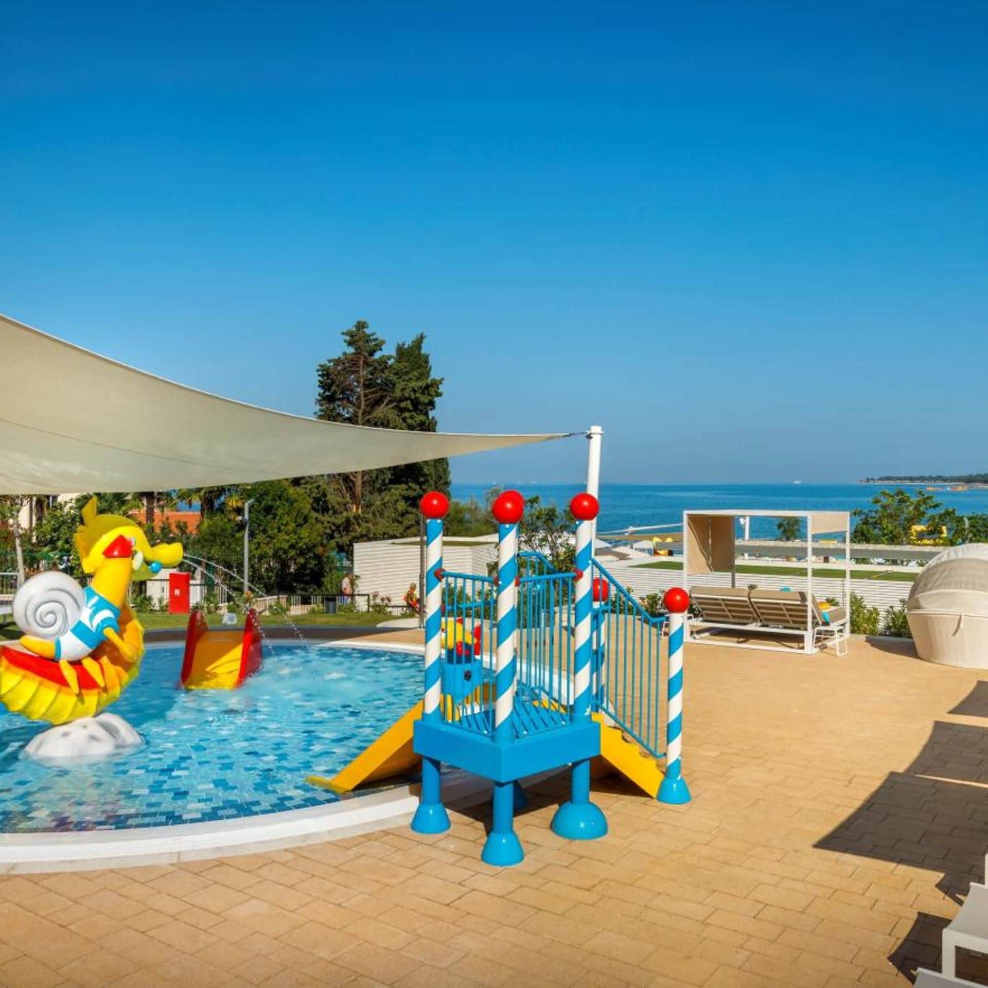 Ein Kinderspielbereich mit Pool, Rutschen und einer Wasserspielanlage.