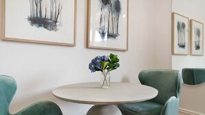 A dining area with a round table, two teal chairs, and a vase with blue flowers. - Cozy Studio with Balcony in Unbeatable Location (Glebe)