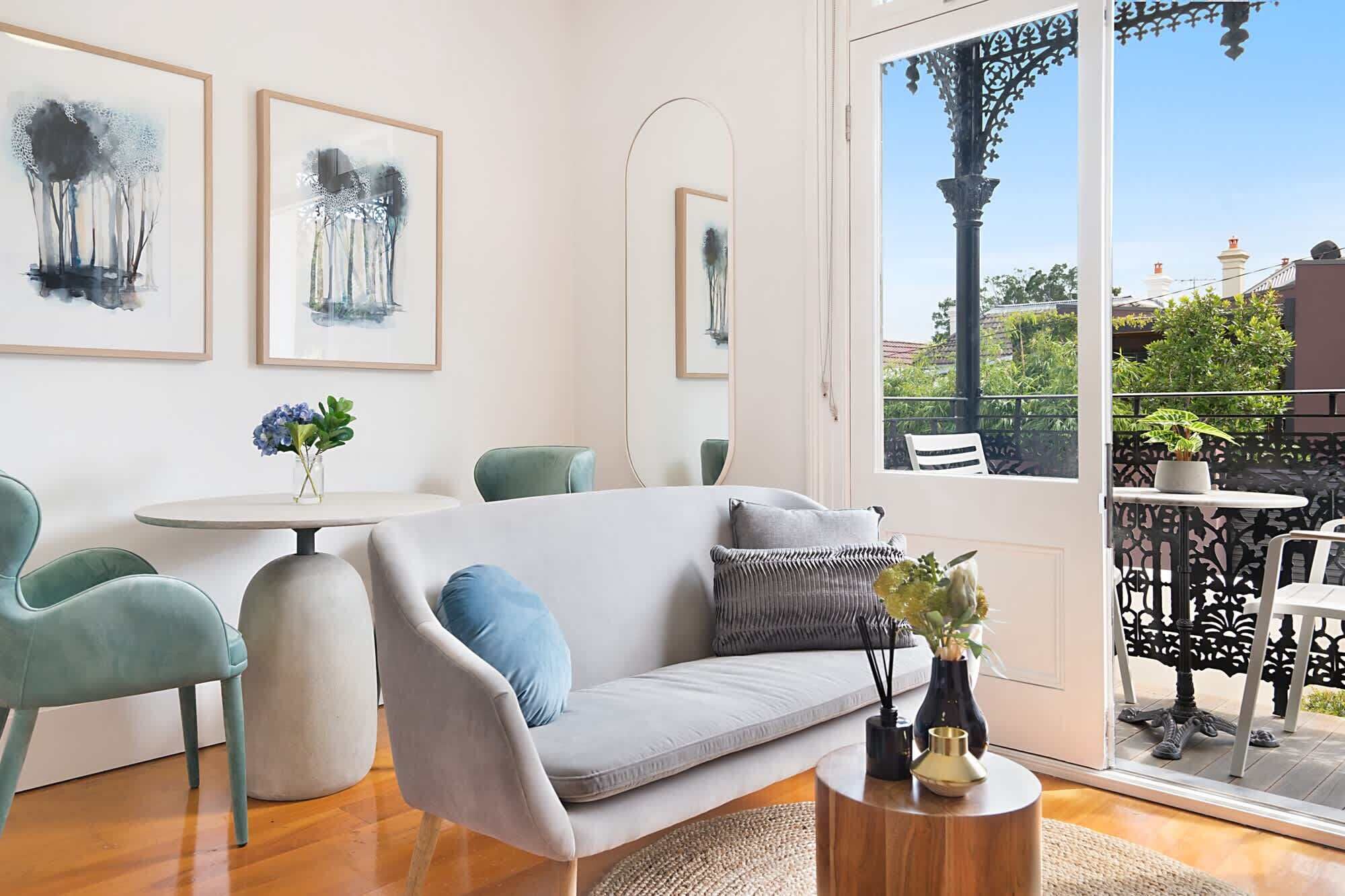 A modern living room with a sofa, chairs, a round table, and artwork on the walls.