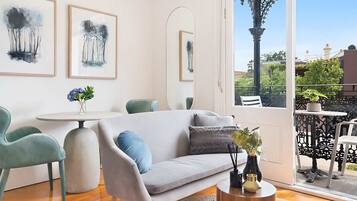 A modern living room with a sofa, chairs, a round table, and artwork on the walls.