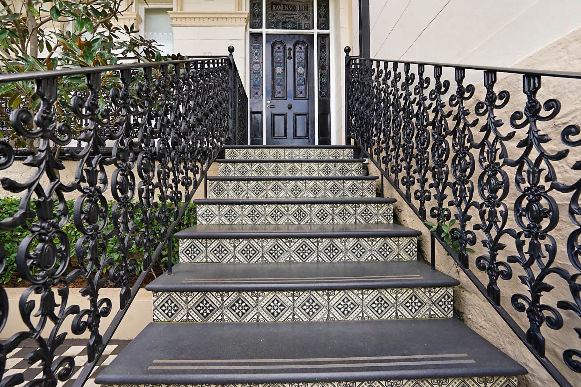 A staircase with ornate black metal railings and patterned tile steps leading to a door labeled "Ravenscourt."