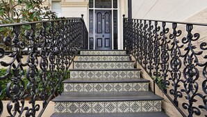 A staircase with ornate black metal railings and patterned tile steps leading to a door labeled "Ravenscourt." - Cozy Studio with Balcony in Unbeatable Location (Glebe)