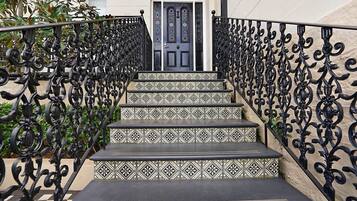 A staircase with ornate black metal railings and patterned tile steps leading to a door labeled "Ravenscourt."