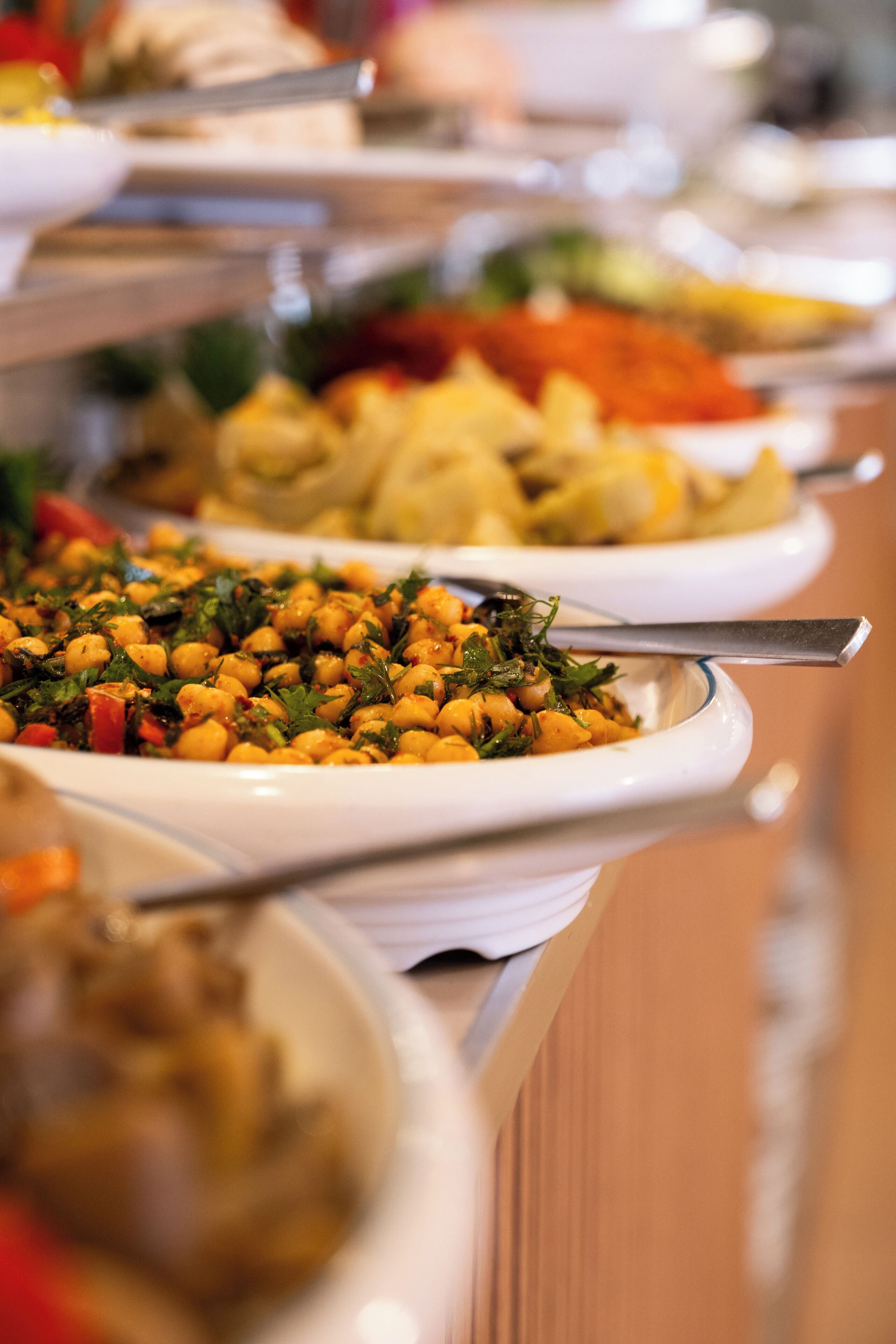 A buffet with various dishes, including a plate with chickpeas and greens.