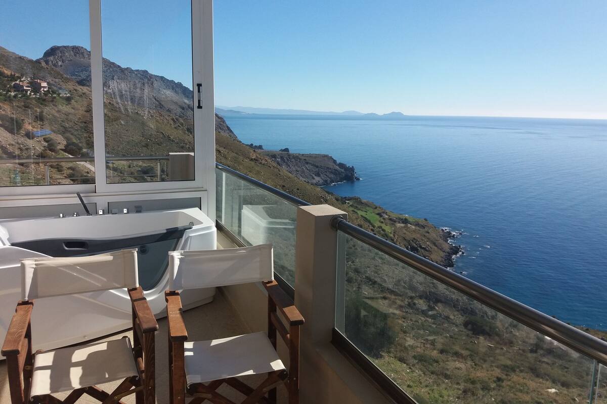 A balcony with a view of the ocean and a mountainous landscape.