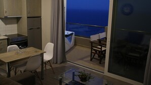 A modern kitchen with a dining area, a balcony with a view of the sea, and a glass table with a vase. - Akrotiri Panorama (Agios Vasileios)