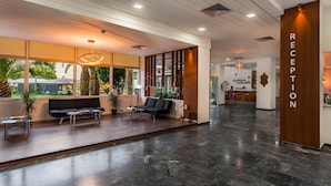 A modern reception area with a marble floor, black sofas, and a reception desk.