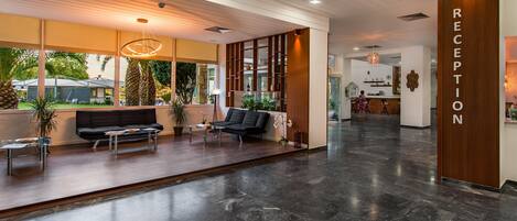 A modern reception area with a marble floor, black sofas, and a reception desk.