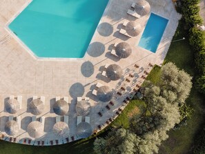Una piscina al aire libre, sombrillas, sillones reclinables de piscina