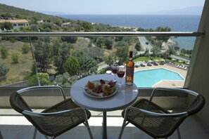 Un balcón con una mesa dispuesta para dos personas, con vista a una piscina y al mar.