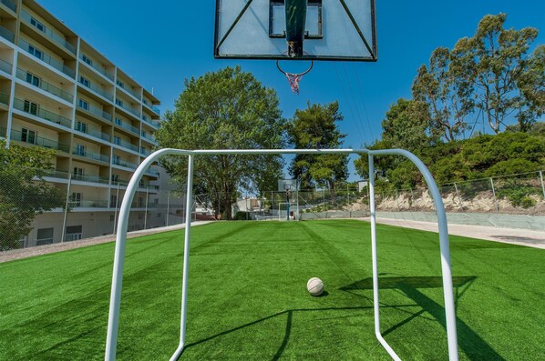 Una cancha de baloncesto con una red, una pelota y un edificio al fondo.