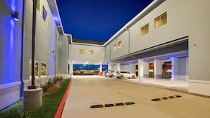 A modern building with a covered parking area and a well-lit entrance. - Scottish Inns & Suites Houston, TX (Houston)