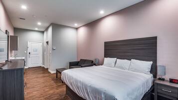 Un dormitorio moderno con una cama grande, mesitas de noche, un escritorio y una silla.