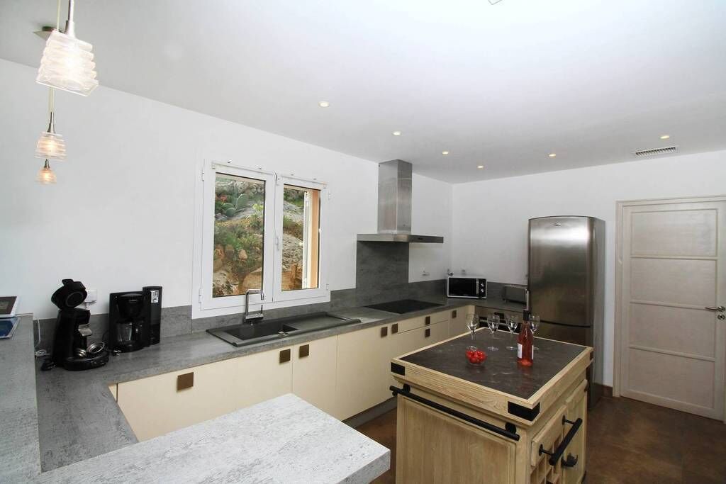 Una cocina moderna con horno empotrado, microondas y refrigerador. Hay una ventana que ofrece vistas al exterior.