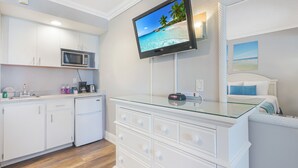 A modern kitchen with white cabinets, a microwave, and a glass-top dining table.
