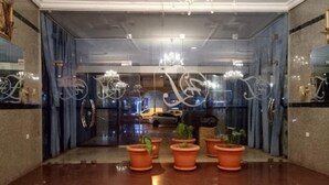 Um hall de hotel com piso lustroso, um candelabro e plantas em vasos.