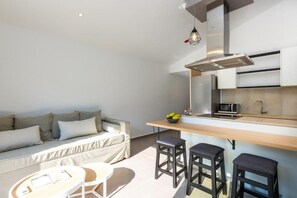 Een knus woongedeelte met een kitchenette, een bank, een eettafel en twee barkrukken.